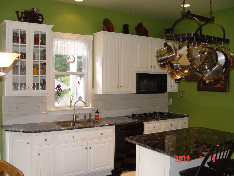 green kitchen with dark granite countertops installed over white cabinets